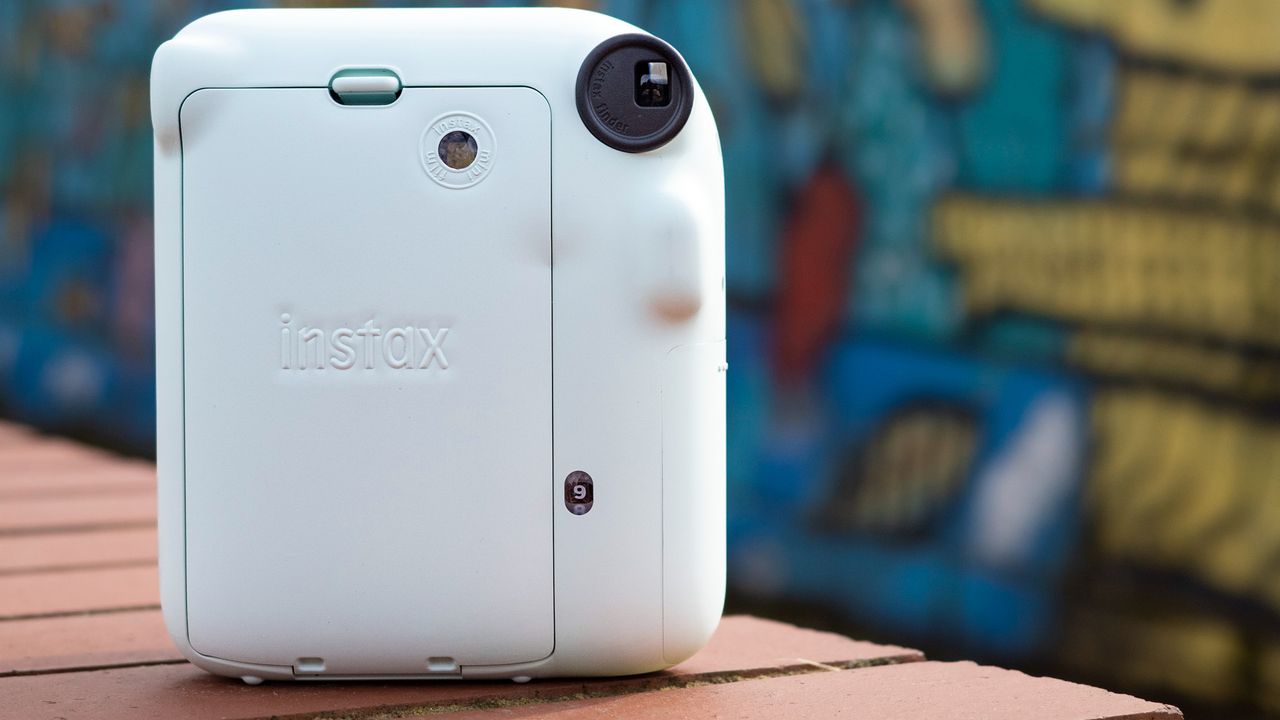 Instax Mini 12 on a brick wall in front of graffiti