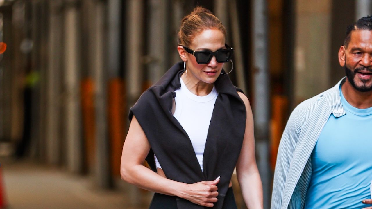 Jennifer Lopez in street style wearing an athleisure tank top and a sweatshirt over her shoulders