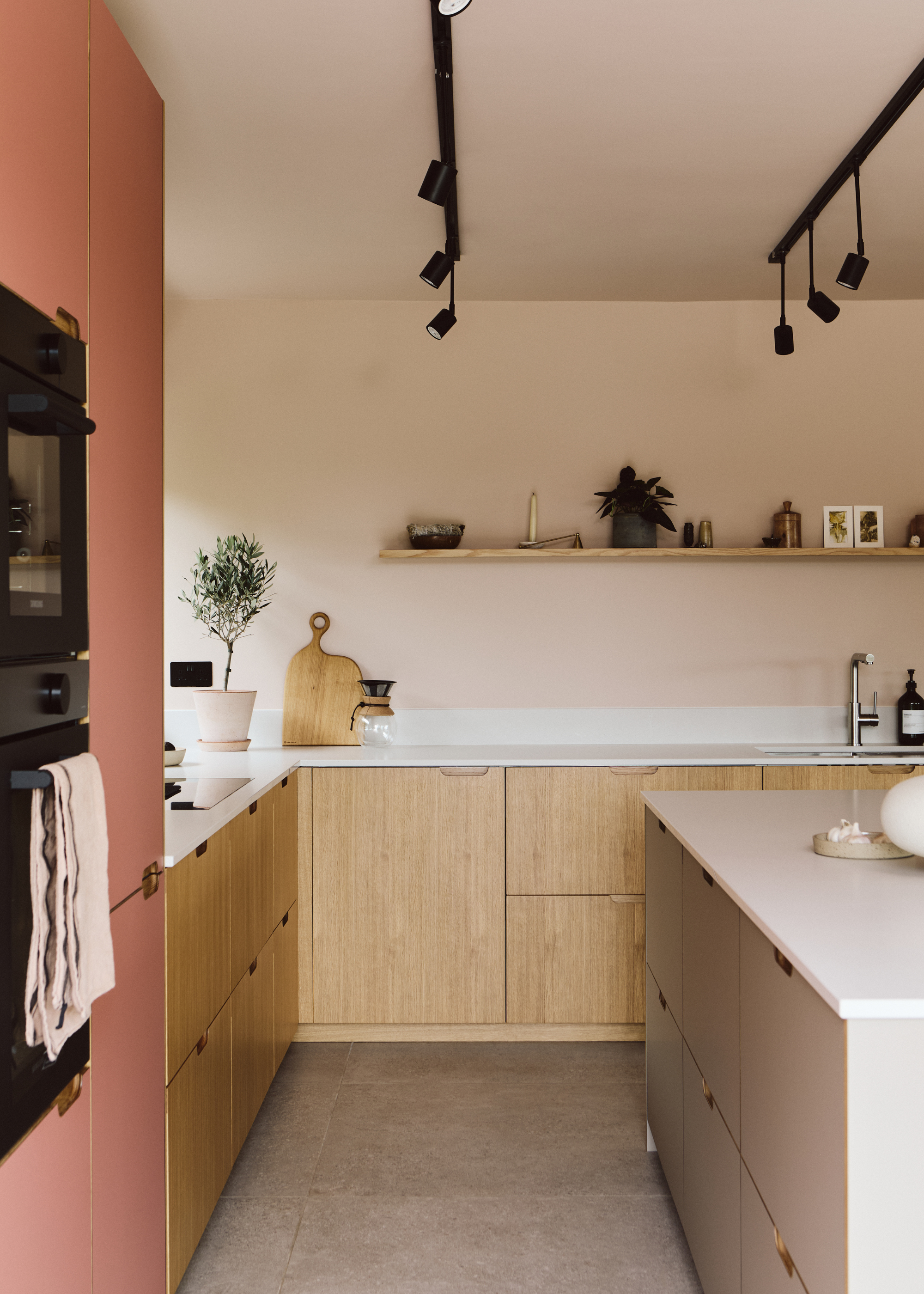 neutral toned kitchen with pink walls and wooden cabinets