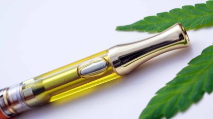 Delta-8 vape pen next to marijuana leaf