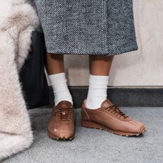 a model wearing the Nike x Aritzia sneaker collaboration on the street with a coat