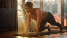 Woman performing mountain climber exercise in living room