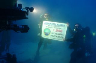 Divers Dave Pence (left) and Ken Longenecker (right) hold up a banner commemorating the Hawaii Undersea Research Laboratory&#039;s 1,000th dive with the Pisces submersibles.