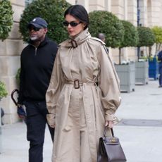 Kendall Jenner wears satin kitten heels in Paris with a funnel neck trench coat.