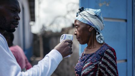 A photo of a health worker at CBCA Virunga Hospital in the DRC checking visitor temperatures in the wake of the Ebola outbreak. 