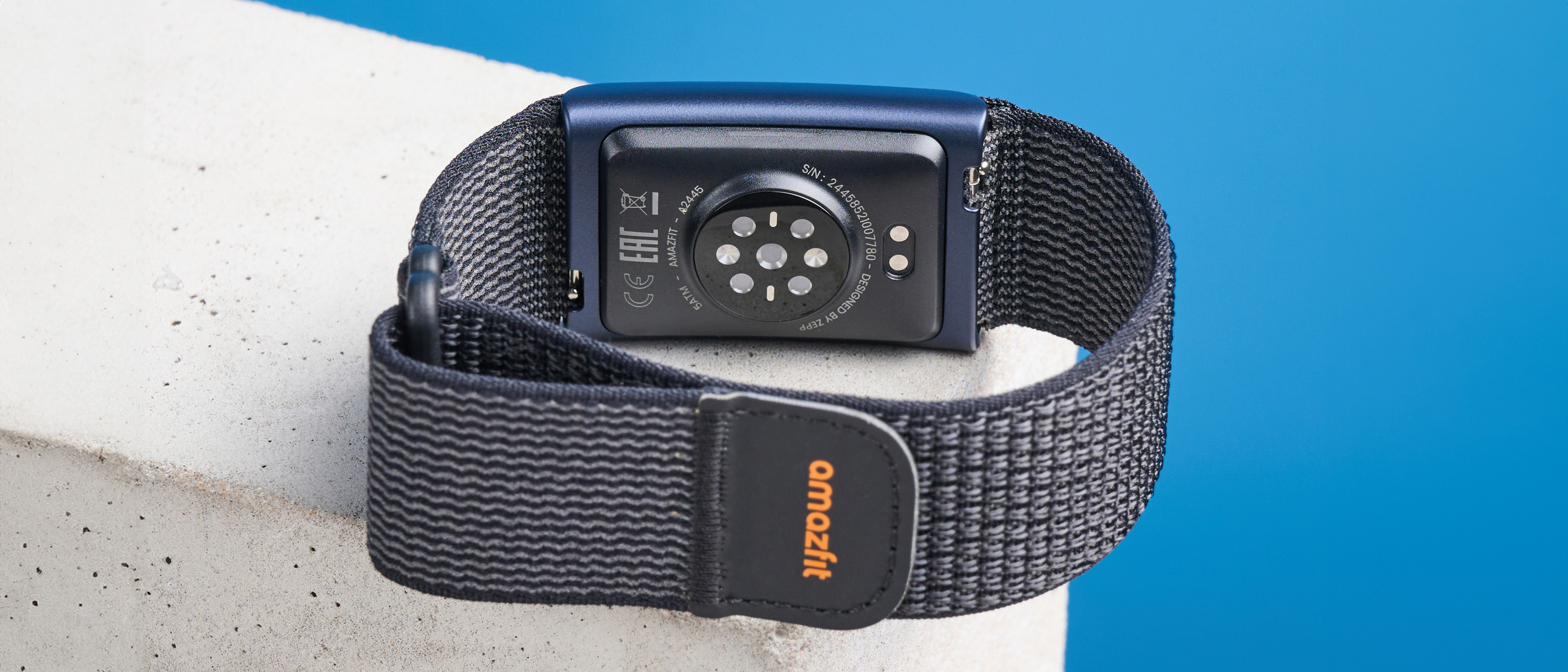 the amazfit helio strap fitness tracker with a screenless design, showing the gray strap worn around the wrist and the charger