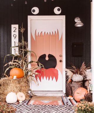 Halloween door decoration depicting a monster-like figure, black wall decor in background and pumpkins