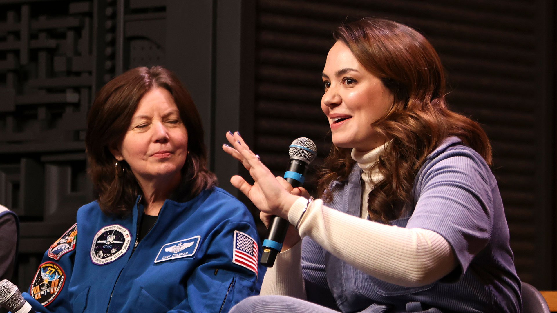 a female astronaut in blue flight jacket and a film director speak at a film festival