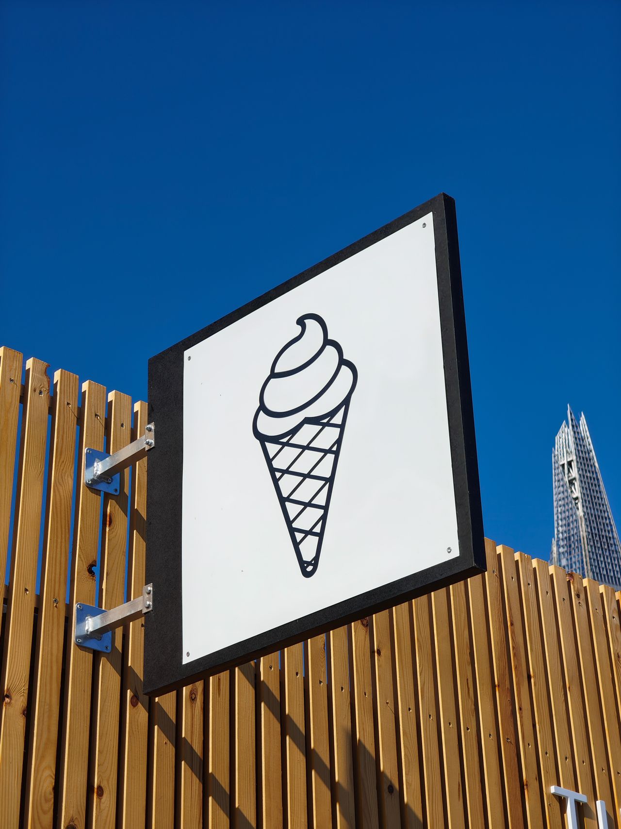 An ice cream sign set in front of a blue sky