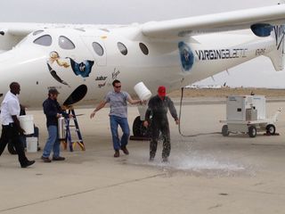 New Virgin Galactic pilot C.J. Sturckow, a four-time space shuttle astronaut, gets a traditional dousing after flying the company's WhiteKnightTwo mothership for the first time on May 9, 2013.