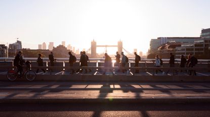 Crowd of business people walking to work with view of Tower Bridge and Canary Wharf behind