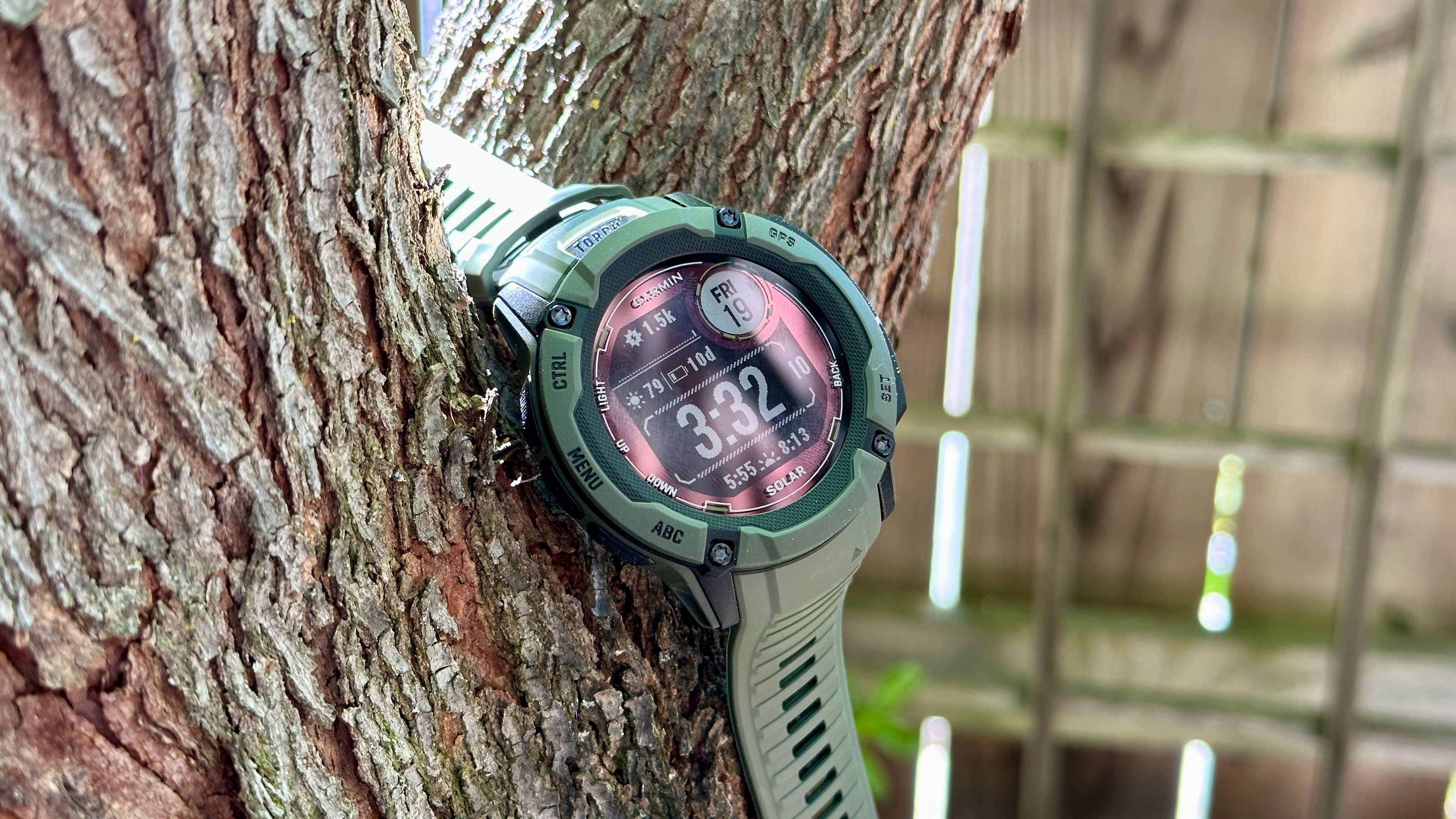 The Garmin Instinct 2X Solar hanging from a tree, showing the main watch face