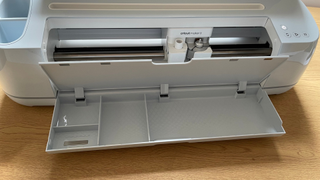 A photo of the Cricut Maker 3 on a desk with its tools slot open, taken for a review
