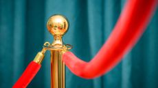 Teal curtains and a gold stanchion with red velvet rope