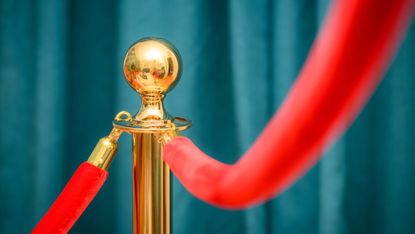 Teal curtains and a gold stanchion with red velvet rope