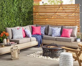 An outdoor L-shaped sectional sofa positioned around a circular fire pit with assortment of outdoor cushion decor