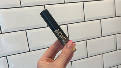 Original image showing a hand holding the MAC Studio Radiance Concealer against a white tiled background 