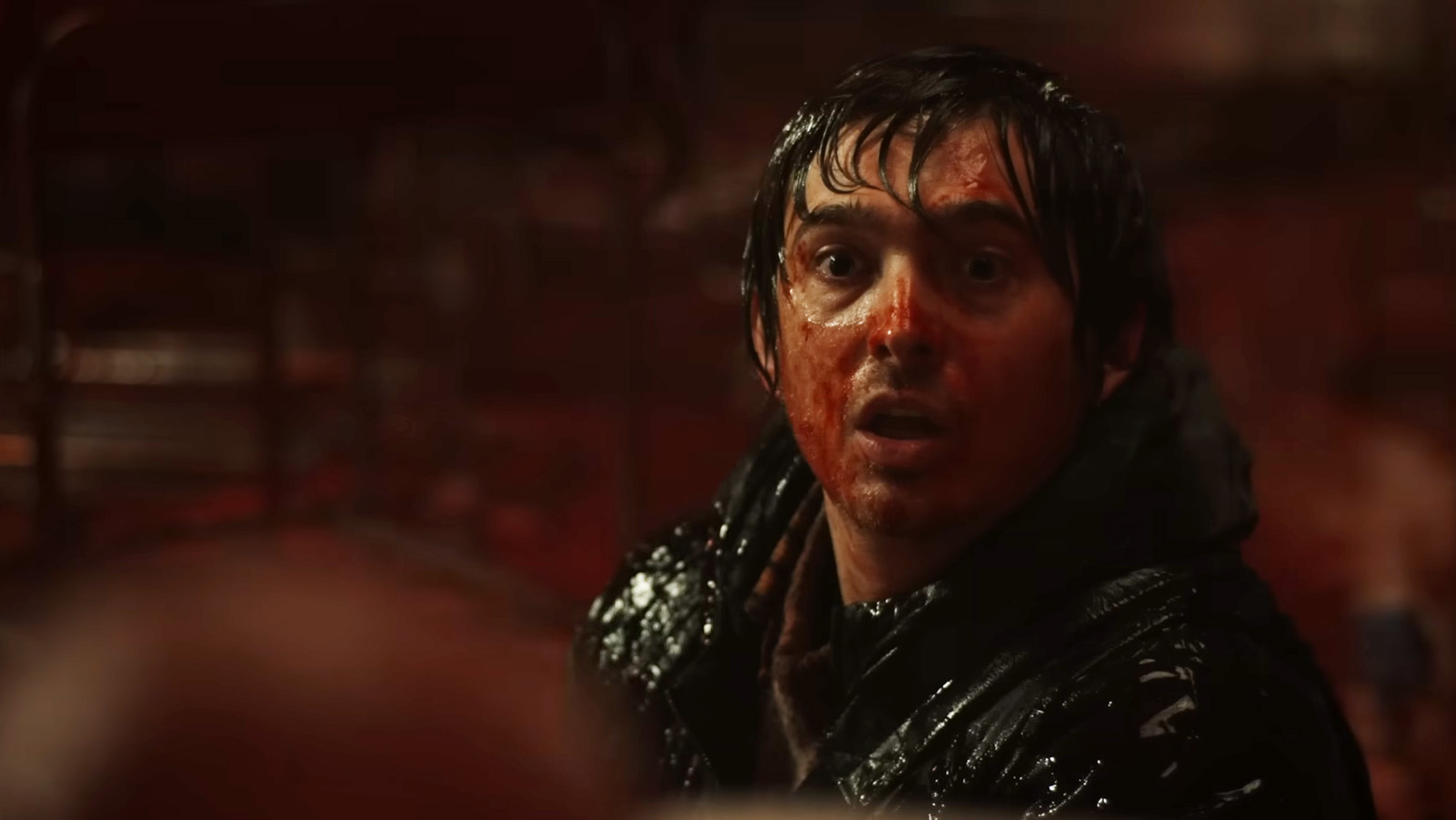 A man with a bloody face looking at something that scares him