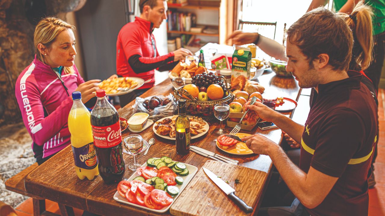 Cyclist sit down at a table to enjoy a meal in cycling kit