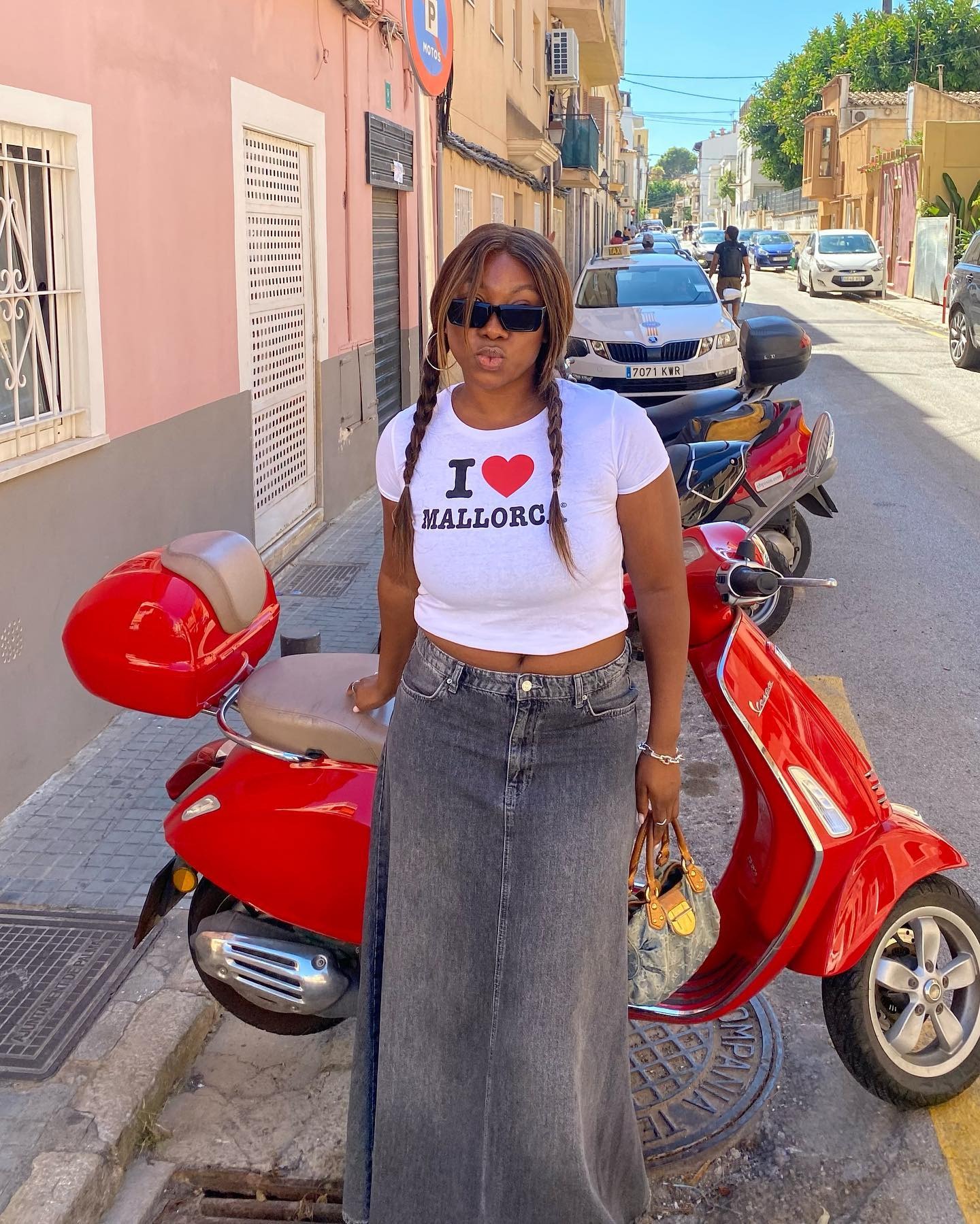 @nnennaechem leaning against a red motorbike wearing pigtail braids