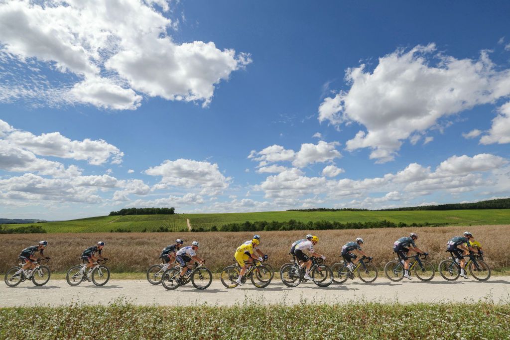 UAE Team Emirates team's Slovenian rider Tadej Pogacar wearing the overall leader's yellow jersey (C) cycles with the pack of riders (peloton) over the Loches-Sur-Ource to Chacenay "Chemin Blanc" (white road) gravel sector 10, during the 9th stage of the 111th edition of the Tour de France cycling race, 199km stage departing and finishing in Troyes, on July 7, 2024. (Photo by Thomas SAMSON / AFP)