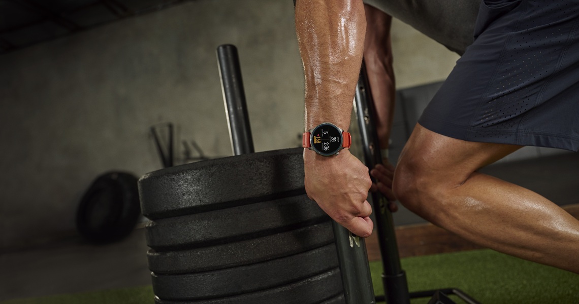 The Amazfit Balance 2 smartwatch on a model's wrist with an orange band during a workout.