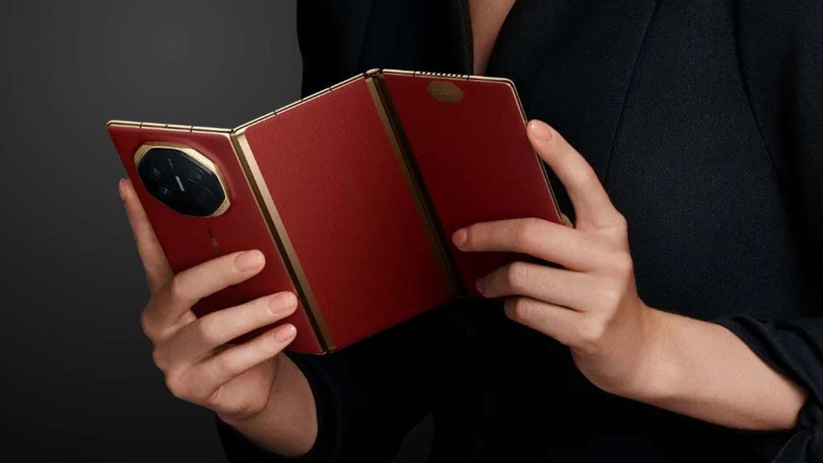 Photograph of hands holding a Huawei Mate XT tri-fold phone with a brown case.