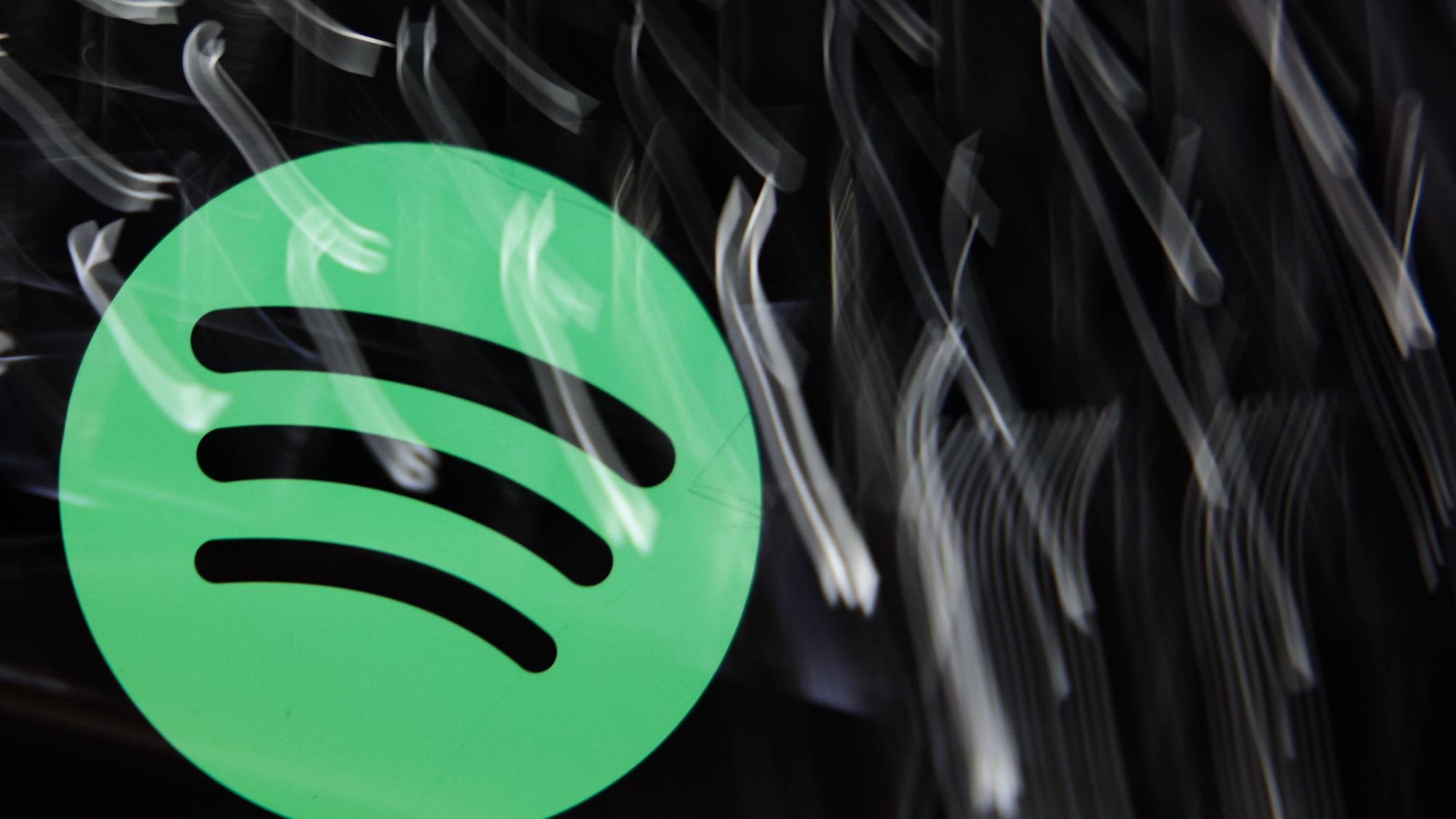 A laptop keyboard and Spotify logo displayed on a phone screen are seen in this multiple exposure illustration photo