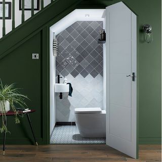 An under stair toilet with grey and white tiles