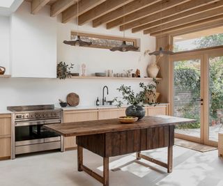 modern rustic kitchen with wooden exposed rafters, wooden cabinets, stainless steel range, wooden vintage style island and large patio doors