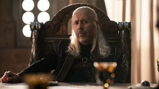 Paddy Considine's Viserys Targaryen stares at a glass of wine as he sits on a chair in House of the Dragon