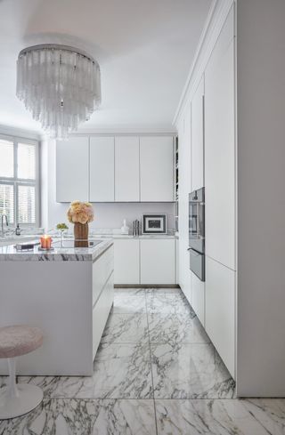 White L-shaped kitchen with marble top and island