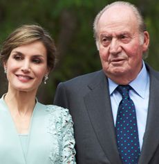 Queen Letizia wearing a mint dress smiling next to King Juan Carlos