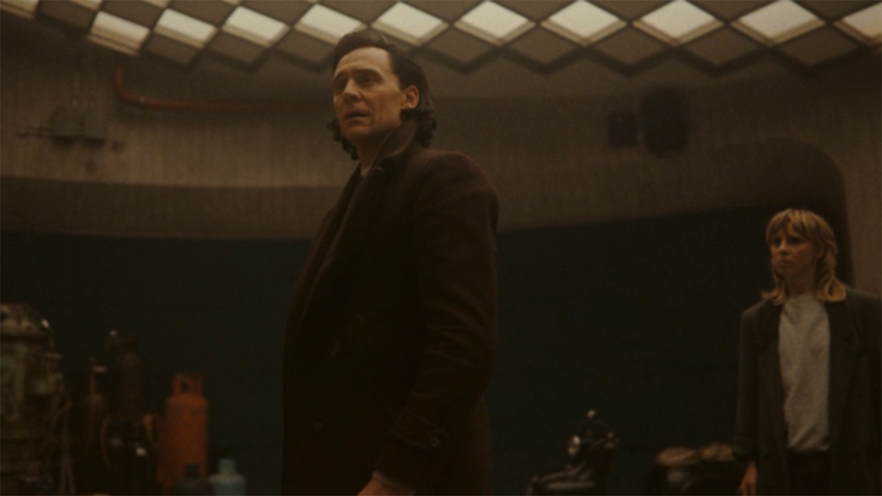 a man in a suit looks confused in a dark library-like room