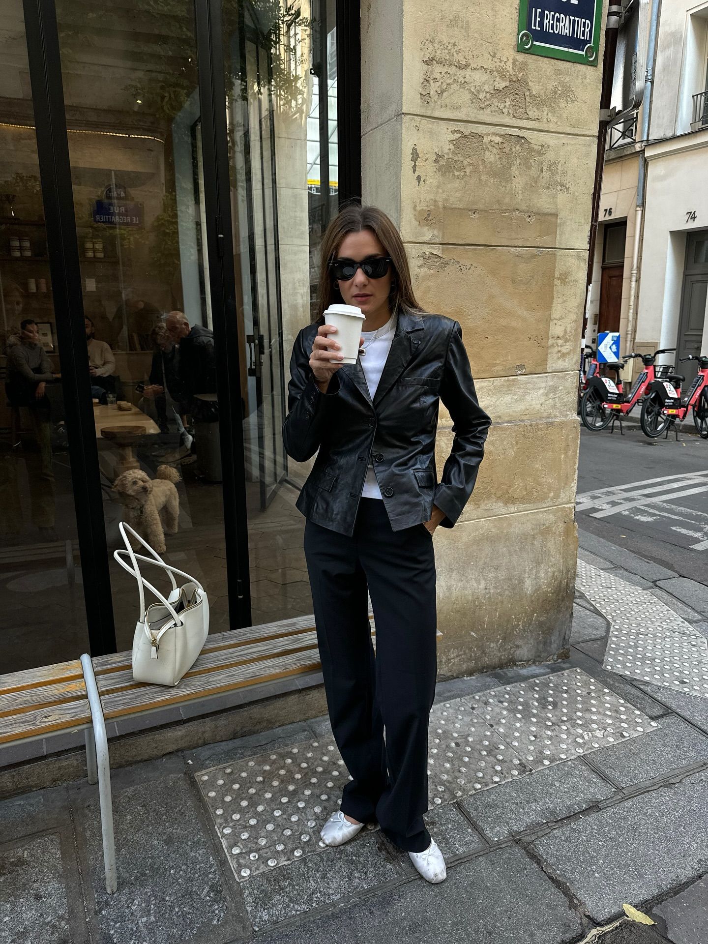 An image of French fashion influencer @annelauremais wearing cigarette trousers with satin ballet flats and a waisted black leather jacket while in Paris.