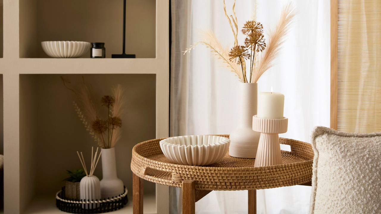 Viral fluted bowl on a rattan side table with candle holder and white vase.