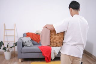 Man holding laundry basket to pick up clutter