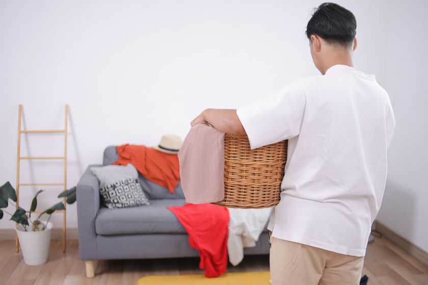 Man holding laundry basket to pick up clutter