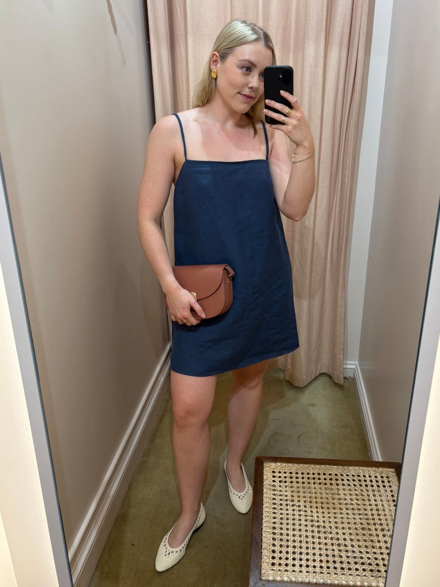 Woman wears linen dress, handbag and white ballet pumps