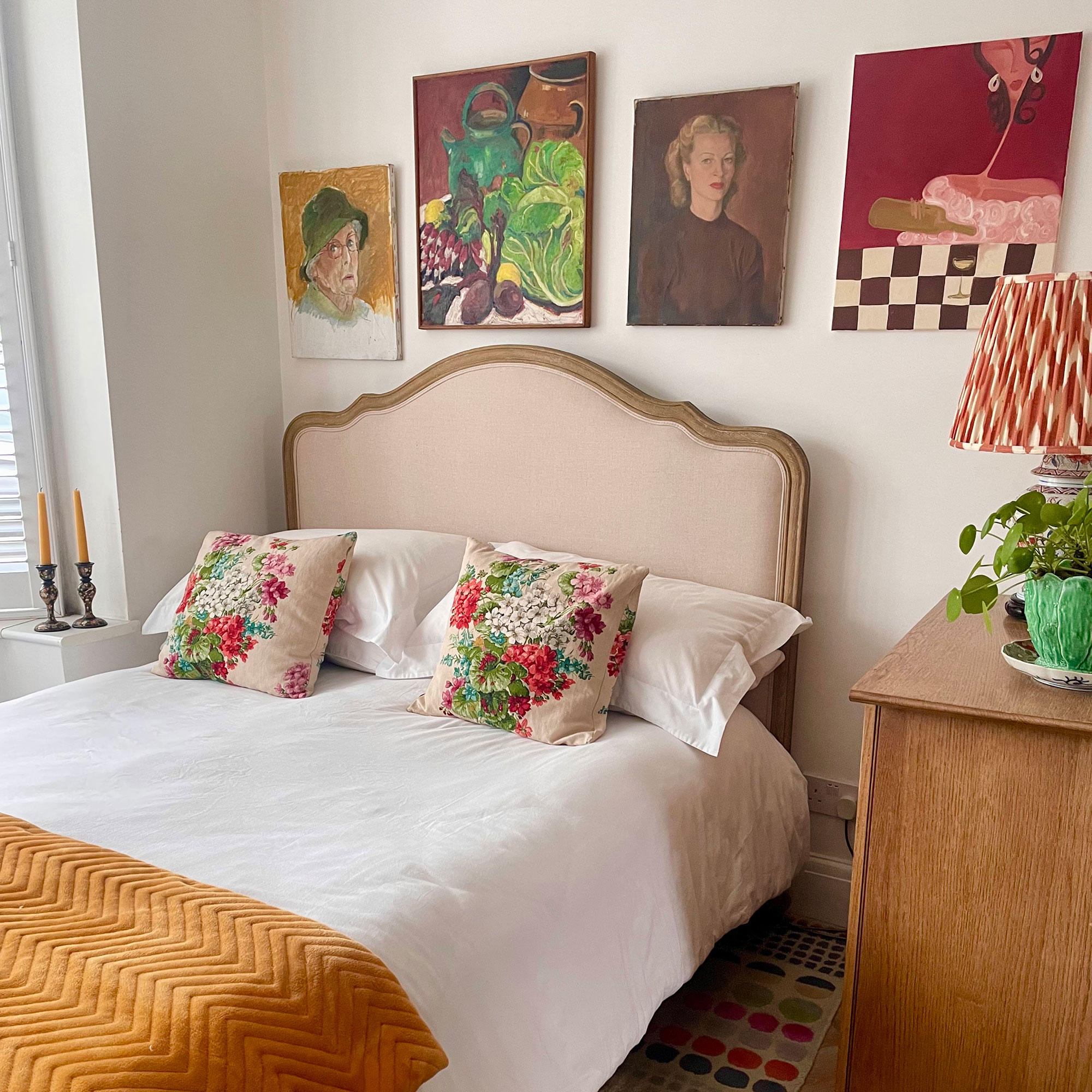 Bedroom area with gallery wall above and floral cushions on bed