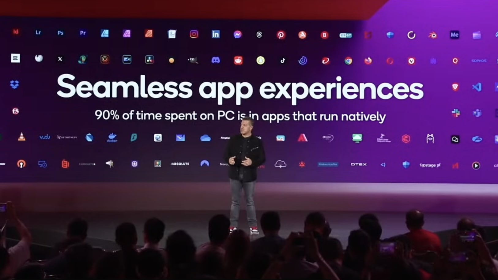 Alex Katouzian, Group General Manager, Mobile, Compute, & XR (MCX), Qualcomm Technologies, standing in front of a video screen touting the seamless app experiences on Snapdragon X Elite powered laptops.