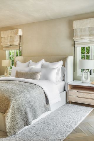 Neutral bedroom in a modern house renovation with a large beige headboard and gray bedding