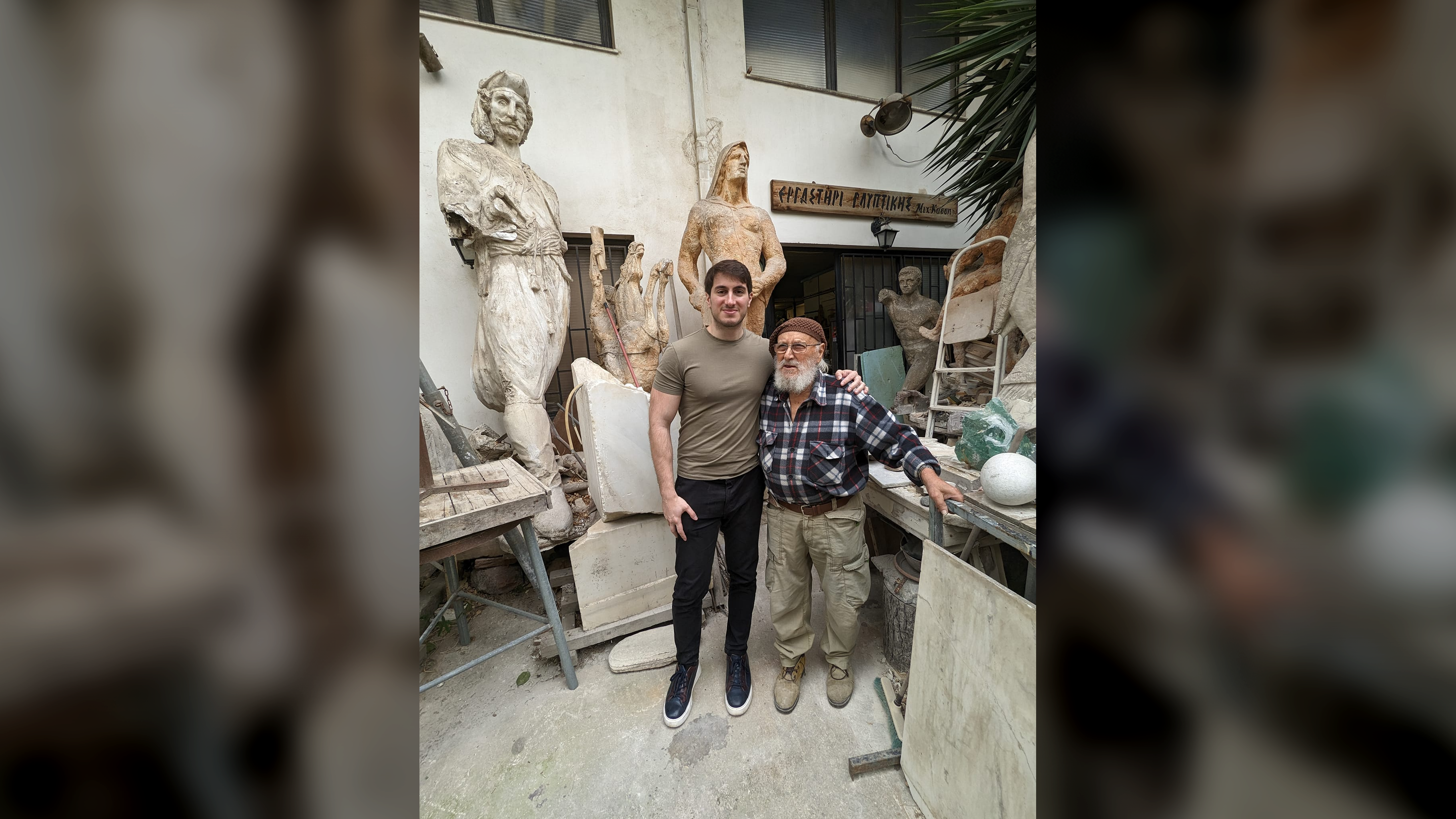 two men stand in a sculpture workshop