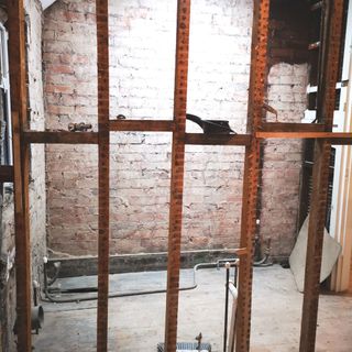 gutted bathroom with exposed brick and missing a wall