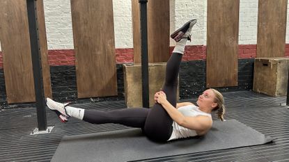 Woman doing scissor kicks in gym on yoga mat