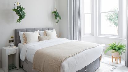 Grey and pastel bedroom with framed artwork above headboard