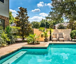 A backyard pool and two chaises longues