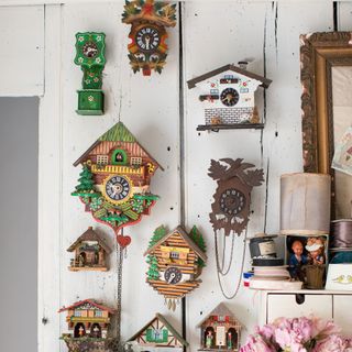 collection of vintage cuckoo clocks on a panelled wall