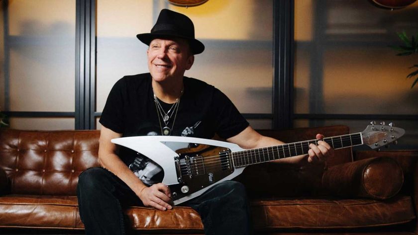 Stephen Dale Petit seated on a leather sofa with a guitar