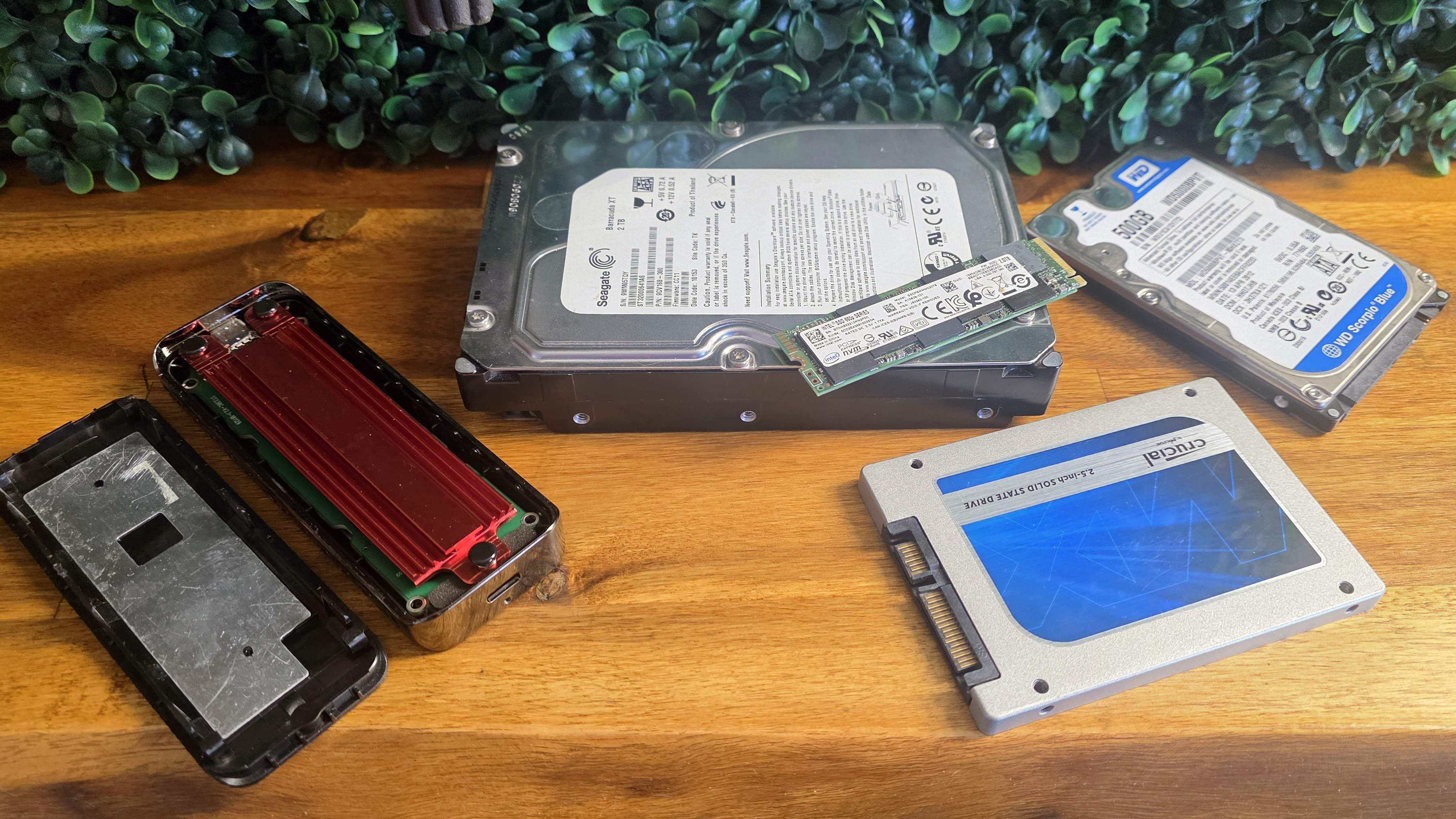 Old SSDs and hard drives on a shelf with an M.2 SSD enclosure
